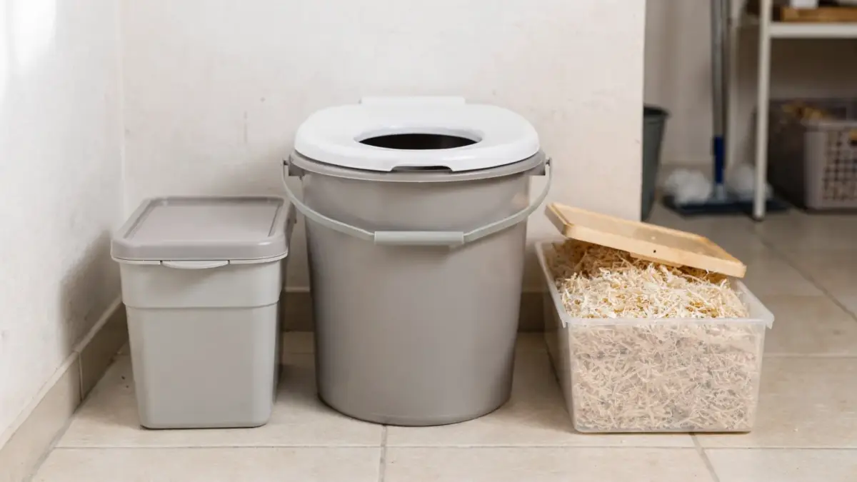 Kompakte Trockentoilette mit Eimer, Sitzaufsatz und Streumaterial in einer Mietwohnung