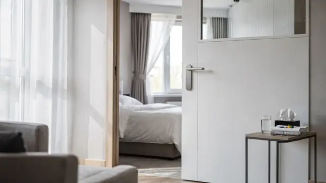 Abgetrennter Wohnraum mit geschlossener Tür, Bett und kleinem Tisch für eine Isolationszone in der Wohnung.